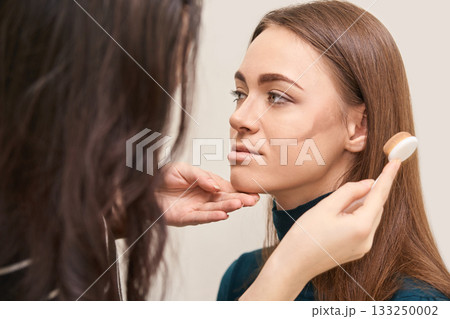 Young caucasian female receiving makeup contouring tutorial from artist Young caucasian female receiving makeup contouring tutorial from artist 133250002