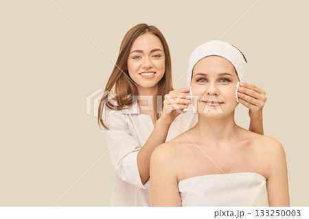 Female spa treatment: caucasian young woman enjoying facial care by female 133250003