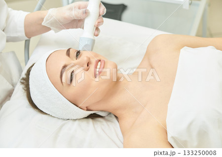 Caucasian young female receiving facial treatment in spa clinic Caucasian young female receiving facial treatment in spa clinic 133250008