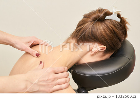 Female receiving relaxing massage therapy on neck and shoulders in spa setting Female receiving relaxing massage therapy on neck and shoulders in spa setting 133250012