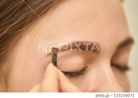 Close-up of young caucasian female applying eyebrow makeup for a natural look 133250071