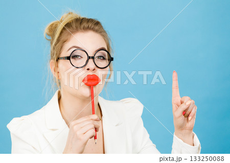 woman holds fake lips on stick pointing at copy space 133250088