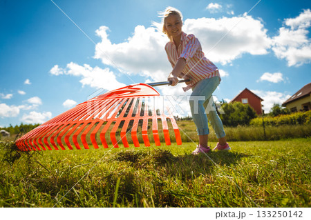 Unusual angle of woman raking leaves Unusual angle of woman raking leaves 133250142