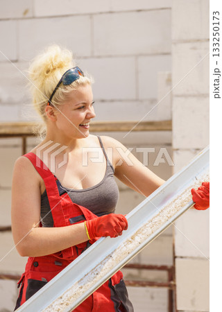 Woman carrying gutter on construction site 133250173