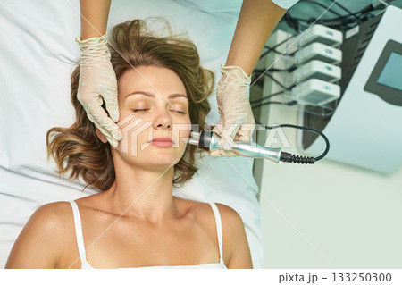 Young caucasian female receiving facial treatment at spa with professional 133250300