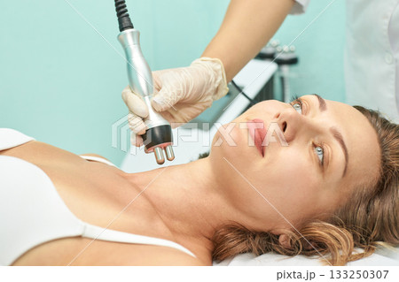 Caucasian female receiving facial radiofrequency treatment in spa clinic Caucasian female receiving facial radiofrequency treatment in spa clinic 133250307