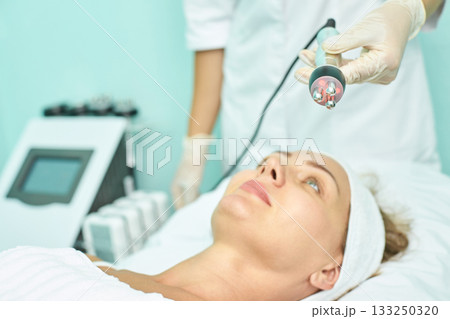 Caucasian mature woman receiving facial treatment in spa clinic by professional Caucasian mature woman receiving facial treatment in spa clinic by professional 133250320