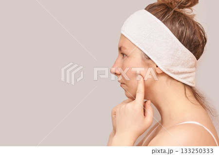 Young caucasian female with headband touching face on light background Young caucasian female with headband touching face on light background 133250333