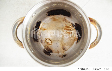 Burnt food in a saucepan, close-up. Black burnt food deposits on non-stick coating, harm Burnt food in a saucepan, close-up. Black burnt food deposits on non-stick coating, harm 133250578