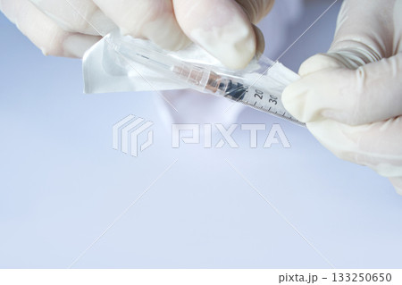 Hands opening sterile syringe pack in medical setting with white background Hands opening sterile syringe pack in medical setting with white background 133250650