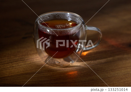 A steaming cup of herbal tea resting on a wooden table in the warm glow of afternoon sunlight 133251014