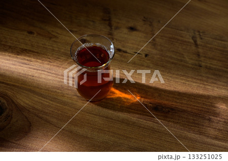 A warm cup of herbal tea resting on a wooden table with soft sunlight illuminating its rich hue in the afternoon A warm cup of herbal tea resting on a wooden table with soft sunlight illuminating its rich hue in the afternoon 133251025