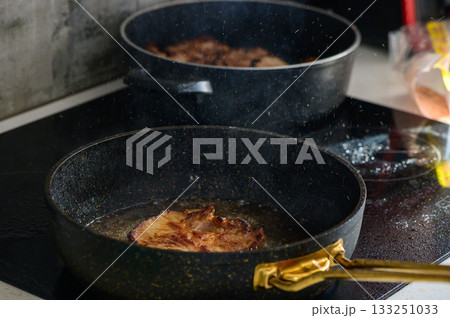 Sizzling pork chops frying in golden oil on a modern stovetop in a cozy kitchen setting at home 133251033