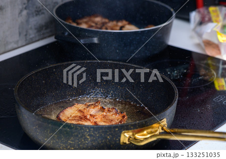 Cooking succulent pork chops in a modern kitchen with sizzling sounds filling the air Cooking succulent pork chops in a modern kitchen with sizzling sounds filling the air 133251035