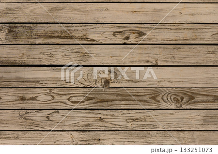 Weathered wooden planks create a rustic backdrop for artistic decor or cozy gatherings. 133251073