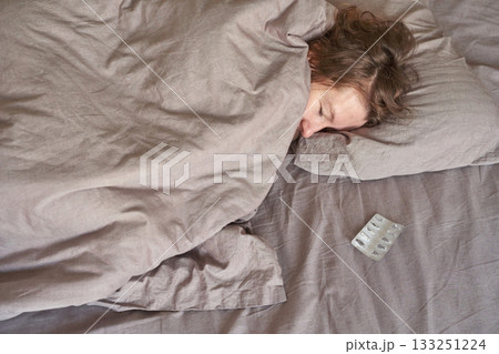 Caucasian female adult sleeping in bed near empty medicine blister pack 133251224