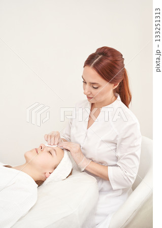 Caucasian female beautician performing facial treatment on young woman in spa Caucasian female beautician performing facial treatment on young woman in spa 133251313
