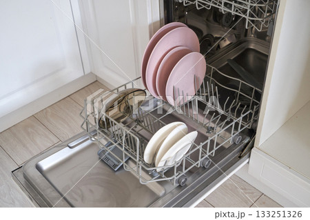 Open dishwasher with clean plates and bowls in kitchen setting Open dishwasher with clean plates and bowls in kitchen setting 133251326