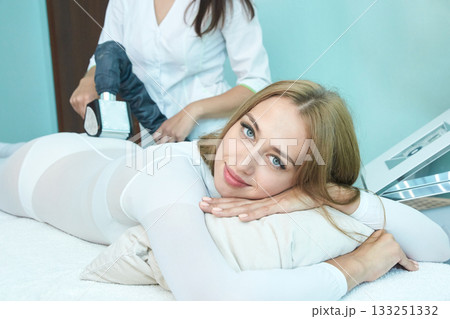 Young caucasian female relaxing during spa treatment with professional masseur 133251332
