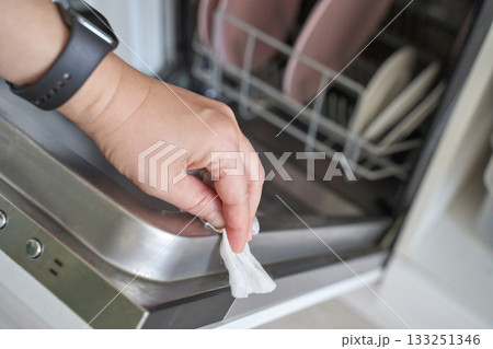 Female hand cleaning dishwasher with wipe in kitchen interior hygiene chores 133251346