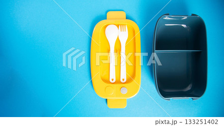 Stylish lunchbox with fork and spoon included on blue background. Copy space for text, portion Stylish lunchbox with fork and spoon included on blue background. Copy space for text, portion 133251402