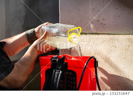 Men's hands pour chemicals into a sprayer to kill parasites on plants. Treatment of plants from diseases and pests. Copy space for text, industry Men's hands pour chemicals into a sprayer to kill parasites on plants. Treatment of plants from diseases and pests. Copy space for text, industry 133251647