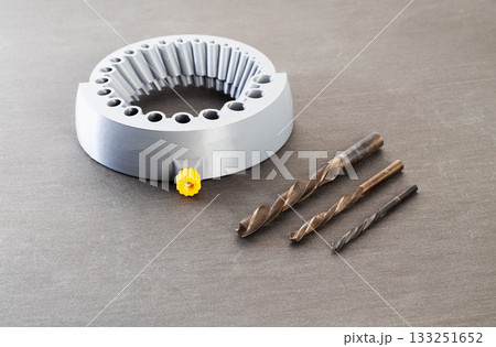 A gray round tool with holes of different sizes for sharpening drills through a grinder, close-up, gray background. Metal drills 133251652