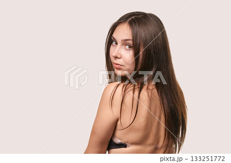 Young caucasian female with long brown hair looking back over shoulder 133251772