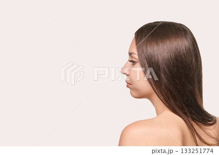Young caucasian female profile with long brown hair against neutral background Young caucasian female profile with long brown hair against neutral background 133251774