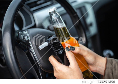 Woman With Beer Bottle And Breathalyzer Sits In Car. Concept Of Drunk Driving Dangers. Woman With Beer Bottle And Breathalyzer Sits In Car. Concept Of Drunk Driving Dangers. 133251856