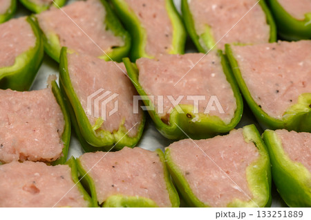 Fresh green bell peppers stuffed with seasoned meat waiting to be cooked in a cozy kitchen 133251889