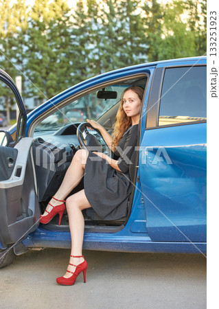 Young caucasian female with long hair in dress and red heels sitting in blue Young caucasian female with long hair in dress and red heels sitting in blue 133251923