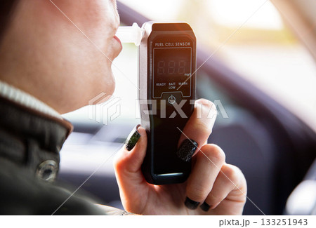 Female Driver Exhaling Into Digital Alcohol Analyzer. Woman Performing Sobriety Self-Test. 133251943