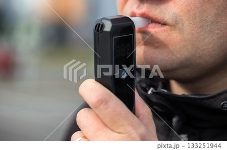 Male Driver Using Personal Alcometer For Sobriety Check. Man Exhaling Into Alcohol Test Device. Driving license revocation for alcohol 133251944