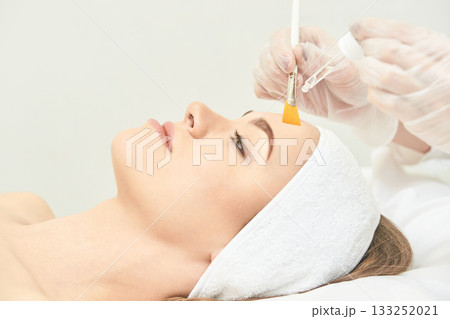 Young caucasian female receiving facial treatment with brush and serum in spa 133252021