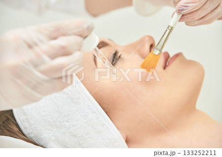 Caucasian female receiving facial treatment with serum and brush in spa 133252211