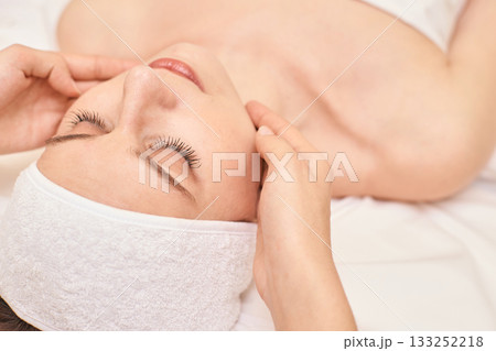 Caucasian female receiving relaxing facial massage in spa setting with calm Caucasian female receiving relaxing facial massage in spa setting with calm 133252218