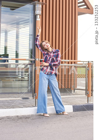 Caucasian female young adult posing in casual plaid shirt and jeans outdoors Caucasian female young adult posing in casual plaid shirt and jeans outdoors 133252253