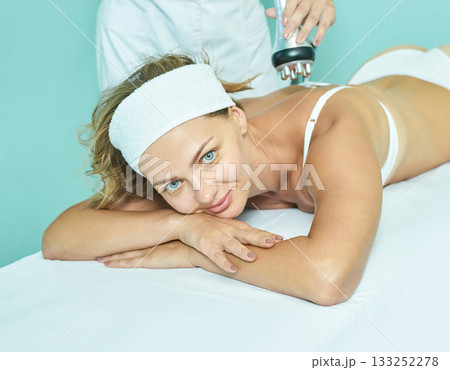 Young caucasian female receiving relaxing spa treatment with facial expression Young caucasian female receiving relaxing spa treatment with facial expression 133252278