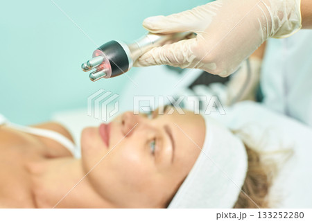 Caucasian young female receiving radiofrequency facial treatment in spa clinic 133252280