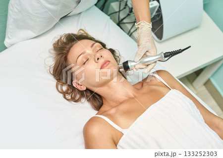 Young caucasian female receiving spa treatment with modern equipment for skin Young caucasian female receiving spa treatment with modern equipment for skin 133252303