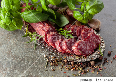 Sliced smoked sausage on a small silver tray. 133252388