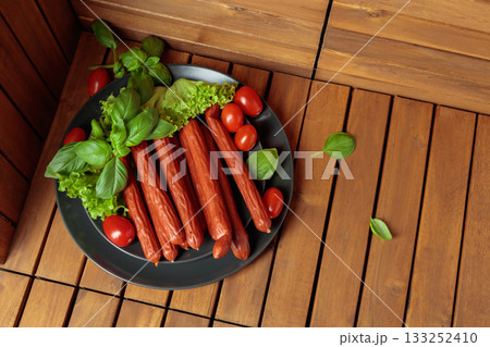 Thin smoked Polish sausages on a black plate. Thin smoked Polish sausages on a black plate. 133252410