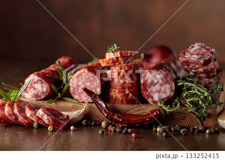Sliced dry cured sausages with peppercorns, thyme, rosemary, and garlic. Sliced dry cured sausages with peppercorns, thyme, rosemary, and garlic. 133252415