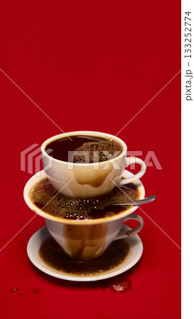 Overflowing stacked coffee cups on bold red background 133252774