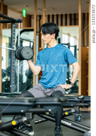 トレーニングジムでダンベルを使って筋トレする若い男性 トレーニングジムでダンベルを使って筋トレする若い男性 133253672