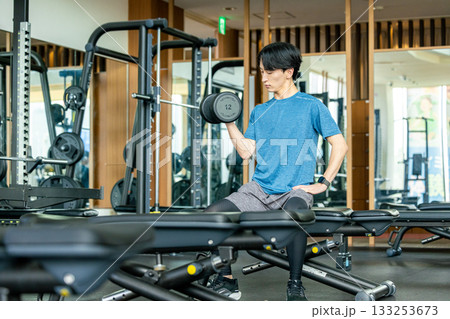 トレーニングジムでダンベルを使って筋トレする若い男性 トレーニングジムでダンベルを使って筋トレする若い男性 133253673