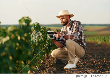 Digital tablet in hands. Farmer is on the agricultural field 133254596