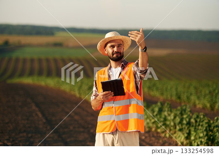 In orange colored uniform. Farmer is on the agricultural field 133254598