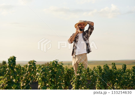Having conversation by phone. Farmer is on the agricultural field Having conversation by phone. Farmer is on the agricultural field 133254630